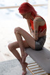 Red-haired anorexic woman with tattoos having pain in stomach