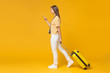 © Damir Khabirov - Full-size portrait of European girl isolated on yellow background walking with suitcase for travelling
