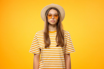 Relaxed european girl in casual clothes standing against yellow background