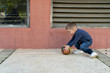 © Miljan Živković - Little boy holding a ball in front of a wall playing on pavement in the city