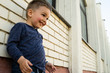 © Miljan Živković - Low angle view on little boy standing on the wall of white bricks smiling