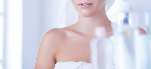 Young woman in bathrobe looking in bathroom mirror