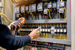 © A Stockphoto - Electrician engineer work  tester measuring  voltage and current of power electric line in electical cabinet control.