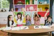© saksit - Group of little preschool kids hands up in class . portrait of children diversity education concept.