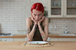 Skinny woman suffering from anorexia sitting in the kitchen