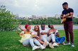 © yurakrasil - Group of smiling happy afro-american friends friends playing guitar outdoors picnic in the campaign