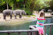 © famveldman - Kids feed elephant in zoo. Family at animal park.