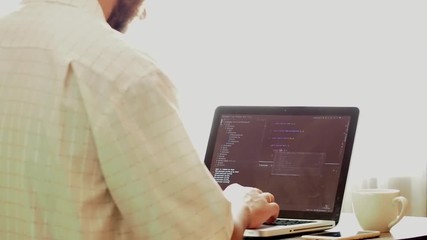 Wall Mural - young programmer coding on a laptop in office