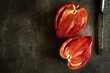 Halved Organic Red Bull's Heart Heirloom Tomato on Rustic Dark Background. Superfood Healthy Eating Concept.