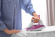 © New Africa - Woman ironing shirt on board indoors, closeup