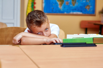 Portrait of a tired schoolboy in the classroom . Concept of education