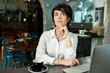 © toxicoz - A middle-aged woman sits in a cafe, drinks coffee and works at a computer. A woman is thinking about something