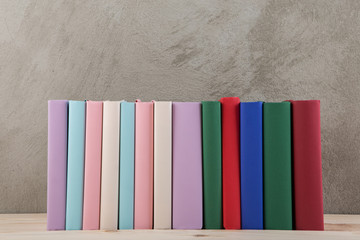 Education and reading concept - group of colorful books on the wooden table, concrete wall blackboard