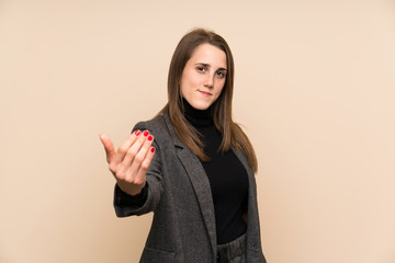 Young woman over isolated wall inviting to come