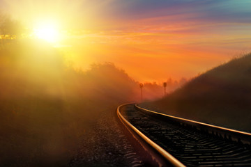 Railroad against beautiful sky at sunset. Industrial landscape with railway station, colorful blue sky, trees and grass, yellow sunlight. Railway junction. Heavy industry. Railways. Cargo shipping