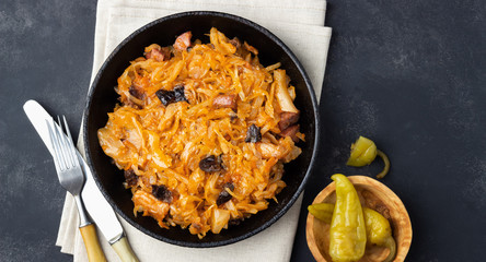 Wall Mural - Traditional dish of polish cuisine - Bigos from fresh cabbage, meat and prunes. Top view. Dark background.