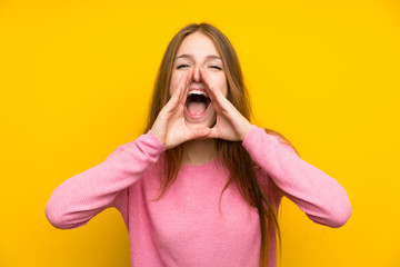 Wall Mural - Young woman with long hair over isolated yellow wall shouting and announcing something