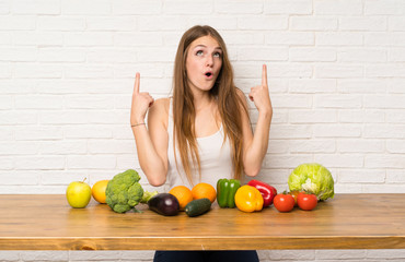 Young woman with many vegetables pointing with the index finger a great idea