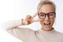 Hey Smile You. Portrait Of Cheeky And Cute Glamour Blond Woman In Glasses Combed Hair And Sweater Winking Happily Showing Peace Victory Gesture As Fooling Around, Being Optimistic