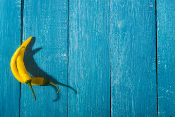 Canvas Print - two yellow chili peppers on blue wooden table background