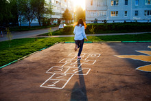 Cute Girl Playing Hopscotch. Sunset. Beautiful Summer, Rest After Work In The Courtyard Of A Multi-storey Building