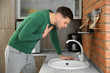 © New Africa - Young man having nausea in kitchen. Feeling sick