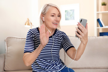 Wall Mural - Mature woman using video chat on mobile phone at home