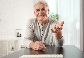 Wall Mural - Mature man using video chat at home, view from web camera