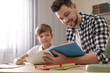 © New Africa - Dad helping his son with school assignment at home