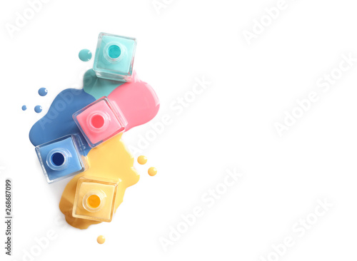Fotomural Spilled different nail polishes with bottles on white background, top view