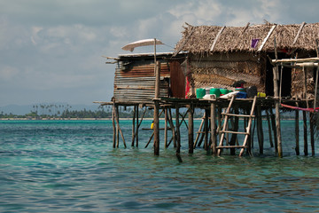 Wall Mural - East Malaysia. island of Borneo. Sea Gypsies relax after a night of fishing in a fishing village, whose huts are built on wooden stilts.