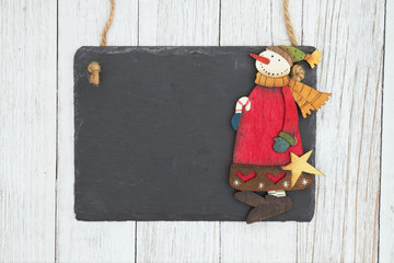 Canvas Print - Blank hanging chalkboard with a snowman on weathered whitewash textured wood background