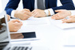 © rogerphoto - Group of business people and lawyers discussing contract papers sitting at the table, close-up. Successful teamwork, cooperation and agreement concepts