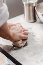 Baker Punchs Down The Dough In The Kitchen In The Bakery