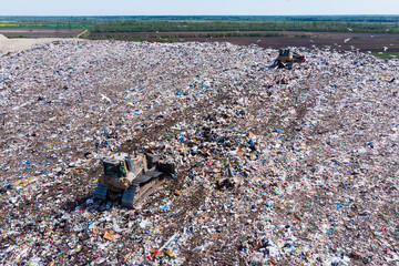 two bulldozer working on mountain of garbage in landfill