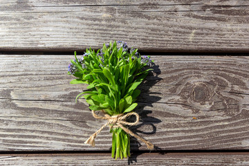 Wall Mural - Small bouquet of blue flowers (forget-me-nots) on old brown wooden background, copy-space