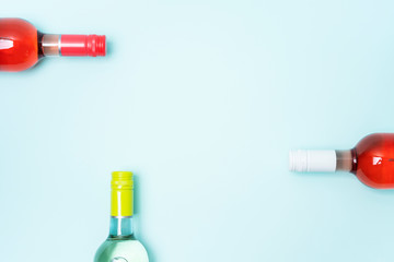 Wall Mural - Mockup frame of bottle foil caps in different bright colors of white and rose wine bottles on blue background with copy space. Minimal abstract colorful mockup concept of alcohol beverage. Flat lay.