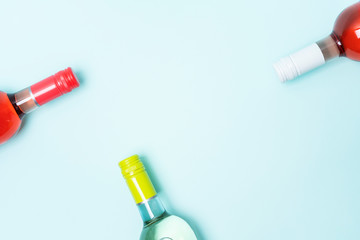 Wall Mural - Layout frame of foil caps in different bright colors of white and rose wine bottles on blue background with copy space. Minimal abstract colorful mockup concept of alcohol beverage. Flat lay.
