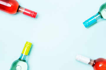 Wall Mural - Mockup frame of bottle foil caps in different bright colors of white and rose wine bottles on blue background with copy space. Minimal abstract colorful mockup concept of alcohol beverage. Flat lay.