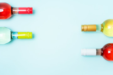 Wall Mural - Screw bottle foil caps in different bright colors of white and rose wine bottles on blue background with copy space. Minimal abstract colorful mockup concept of alcohol beverage. Flat lay.