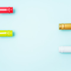 Wall Mural - Screw bottle foil caps in different bright colors of white and rose wine bottles on blue background with copy space. Minimal abstract colorful mockup concept of alcohol beverage. Flat lay.