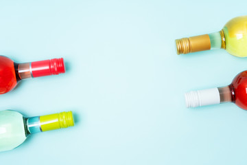 Wall Mural - Mockup frame of bottle foil caps in different bright colors of white and rose wine bottles on blue background with copy space. Minimal abstract colorful mockup concept of alcohol beverage. Flat lay.