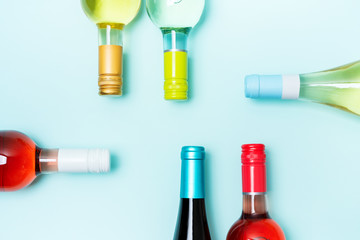 layout frame of foil caps in different bright colors of white and rose wine bottles on blue backgrou