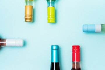 Wall Mural - Screw bottle foil caps in different bright colors of white and rose wine bottles on blue background with copy space. Minimal abstract colorful mockup concept of alcohol beverage. Flat lay.