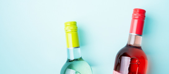 Wall Mural - Screw bottle foil caps in different bright colors of white and rose wine bottles on blue background with copy space. Minimal abstract colorful mockup concept of alcohol beverage. Flat lay.