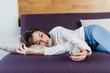 © dianagrytsku - Close up of a relaxed girl using a smart phone lying on a sofa in the living room at home