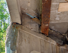 The Underside Of A Highway Bridge Showing Crumbling Cement  Rusting Steel, And Plywood Patches As An Example Of Deteriorating  Infrastructure 