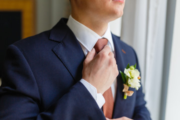 Wall Mural - Elegant businessman sewed to order suit, straightens his tie in an expensive hotel, going to a meeting