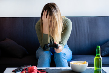 Emotional young woman playing video games at home