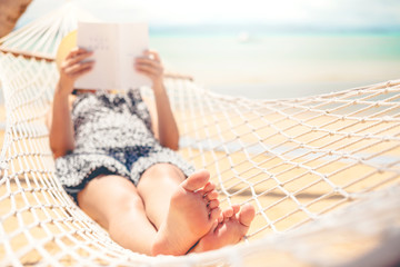 Woman reading a book on hammock beach in free time summer holiday